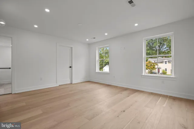 an empty room with wooden floor and windows