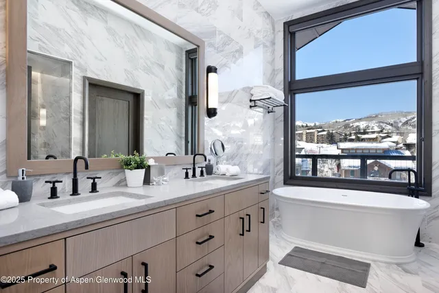 a bathroom with a double vanity sink a large mirror a bathtub and window