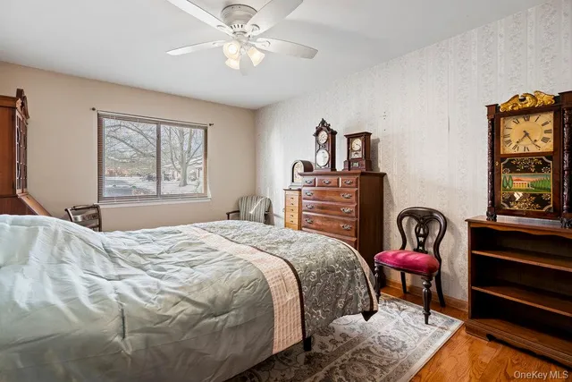 a bedroom with a bed and dresser with wooden floor