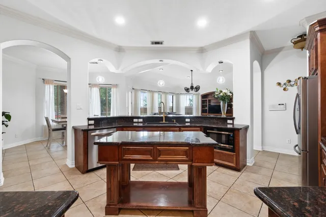 a kitchen with stainless steel appliances granite countertop a stove a sink a refrigerator and a wooden cabinets