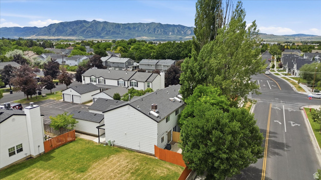 187 West 1190th Street North Logan, UT 84341 - Photo 11 of 12 White siding residence with a fenced backyard, mature trees, and a mountain backdrop