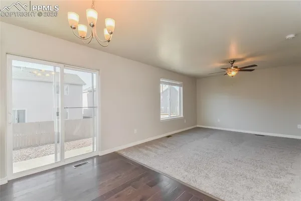an empty room with wooden floor fan and windows