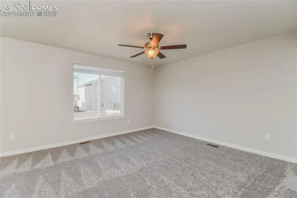 an empty room with windows and fan