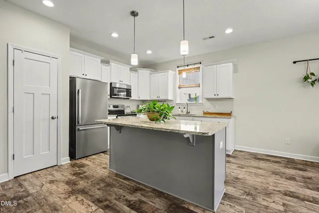 a kitchen with kitchen island a sink stainless steel appliances and refrigerator