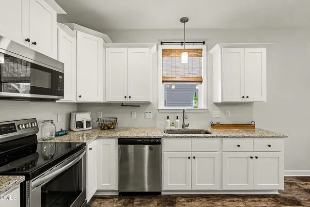 a kitchen with granite countertop white cabinets and stainless steel appliances