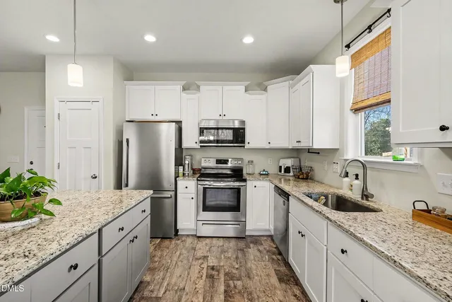 a kitchen with granite countertop white cabinets and stainless steel appliances