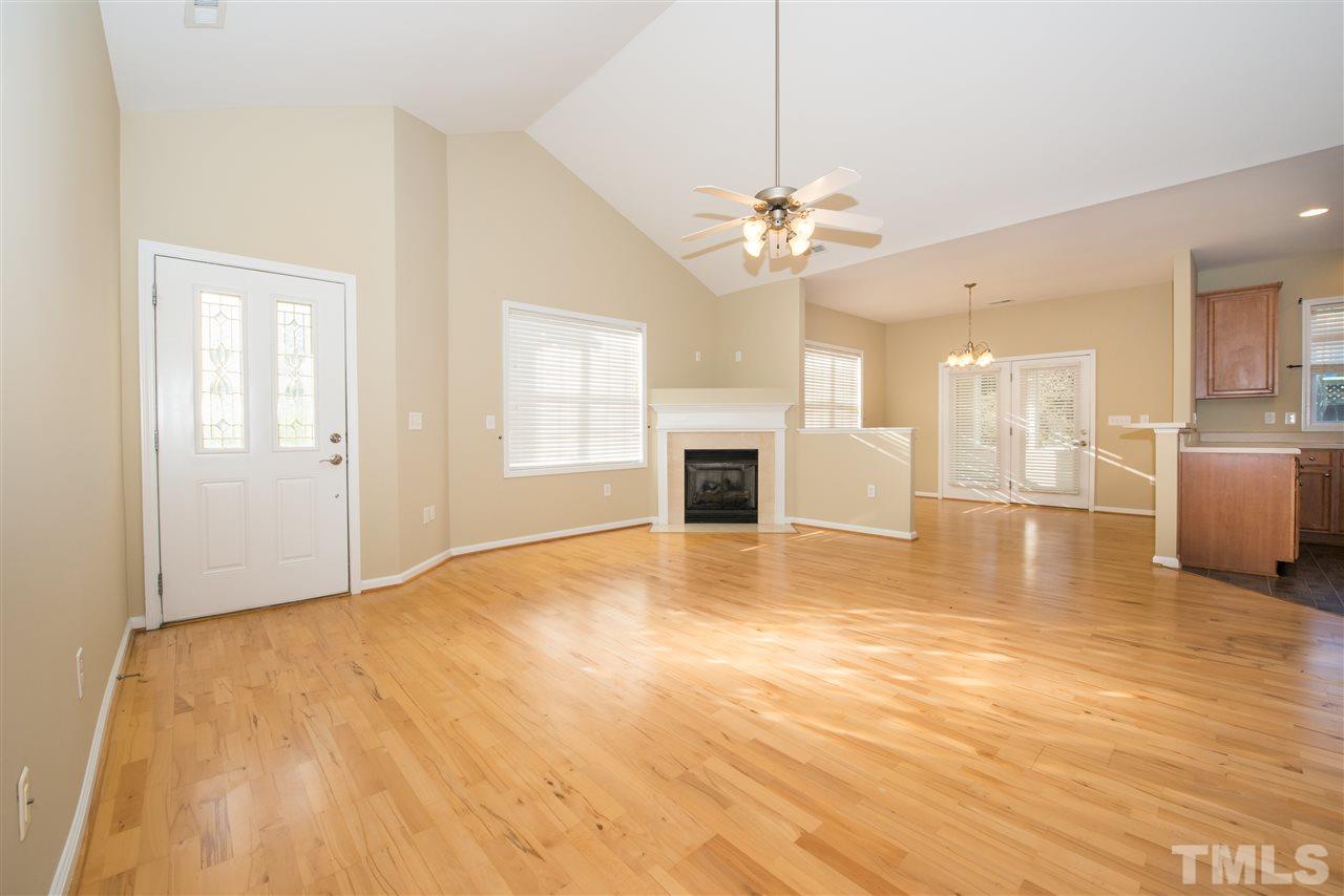 2605 Andover Glen Road Raleigh, NC 27604 - Photo 5 of 17 a view of a livingroom with a fireplace a chandelier and wooden floor