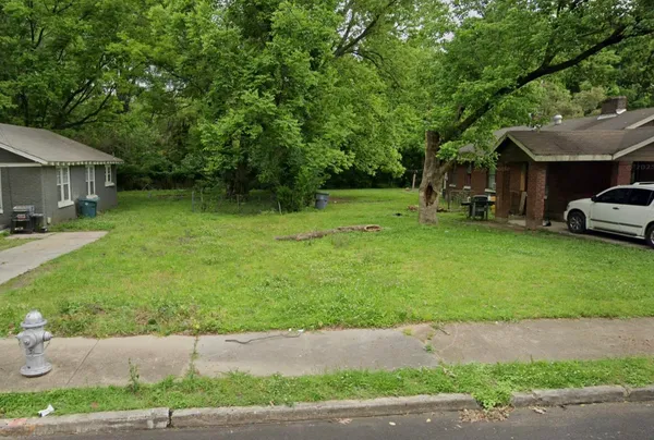 a front view of a house with a garden and trees