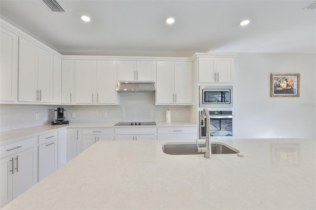 16320 Hidden Oak Loop Bradenton, FL 34211 - Photo 14 of 56 a kitchen with stainless steel appliances a sink a stove a refrigerator cabinets and living room view
