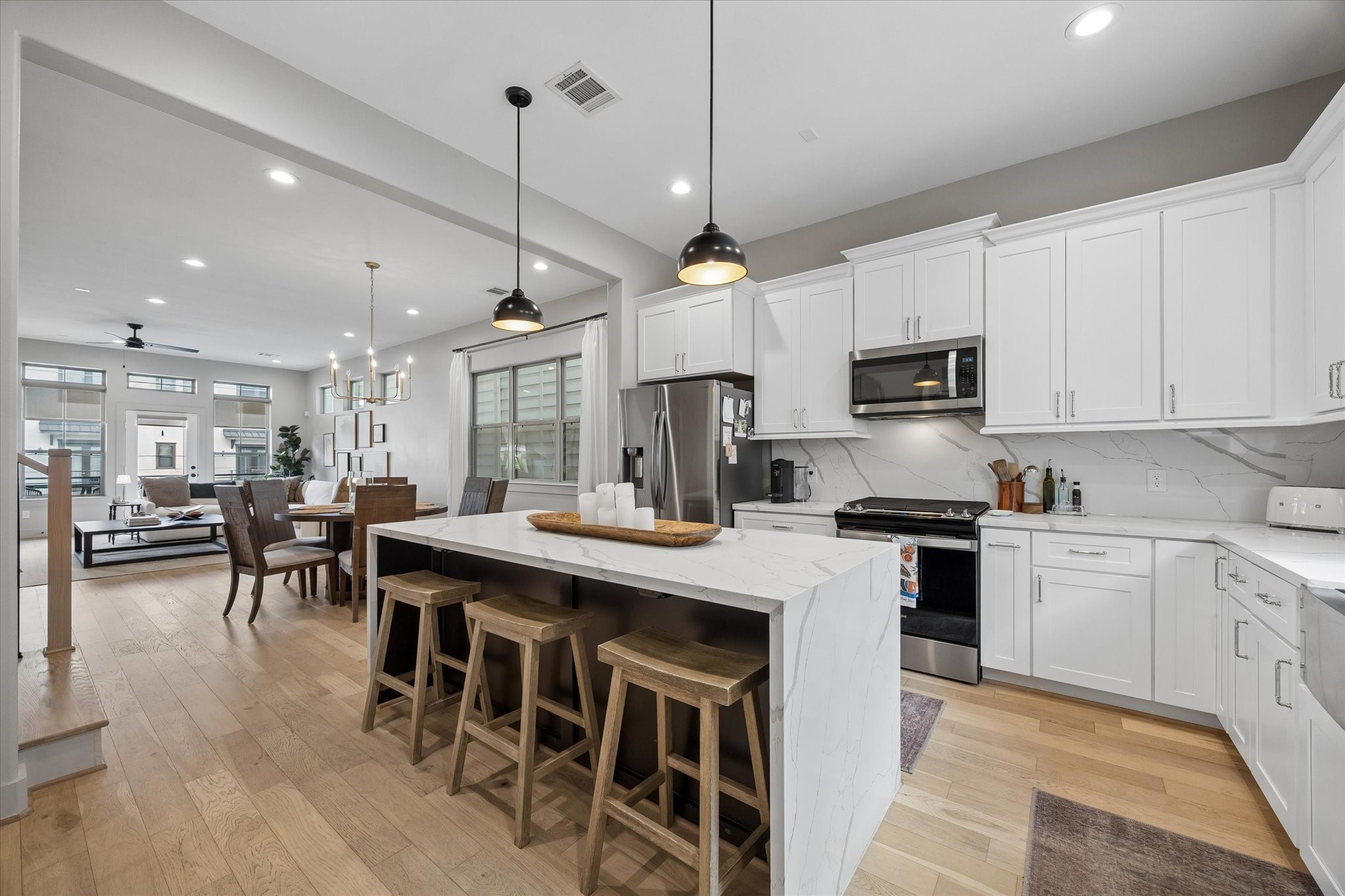 2407 Bevis Street Houston, TX 77008 - Photo 16 of 34 a kitchen with stainless steel appliances granite countertop a stove a refrigerator a kitchen island a dining table and chairs with wooden floor