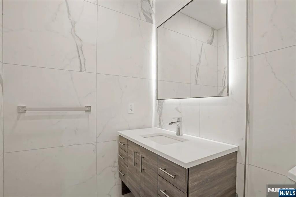 9009 Riverside Place, Unit 1 North Bergen, NJ 07047 - Photo 9 of 12 a bathroom with a sink vanity and a mirror