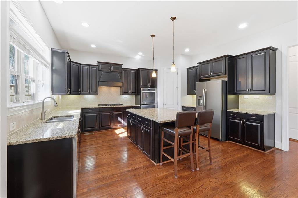 4409 Talisker Lane Acworth, GA 30101 - Photo 16 of 61 a kitchen with stainless steel appliances granite countertop a refrigerator a stove a sink a dining table and chairs with wooden floor