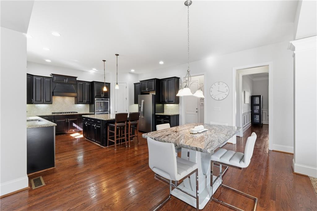 4409 Talisker Lane Acworth, GA 30101 - Photo 19 of 61 a kitchen with stainless steel appliances kitchen island granite countertop a refrigerator a stove a sink a dining table and chairs with wooden floor
