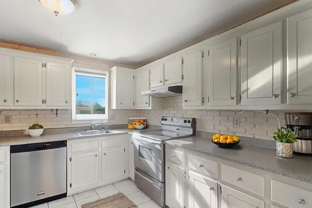 a kitchen with stainless steel appliances white cabinets sink and stove