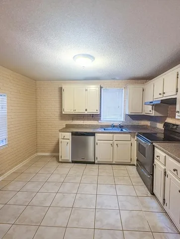 a large kitchen with granite countertop a stove a sink dishwasher and a refrigerator