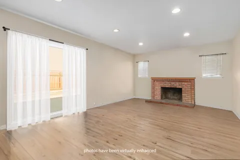 an empty room with wooden floor fireplace and windows