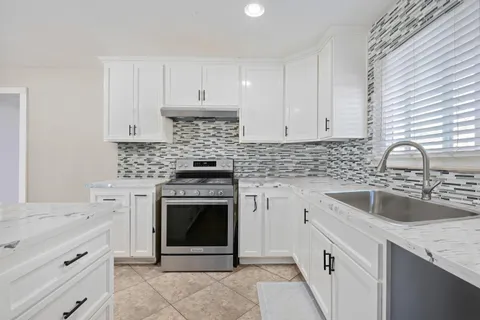 a kitchen with granite countertop a sink stove and cabinets