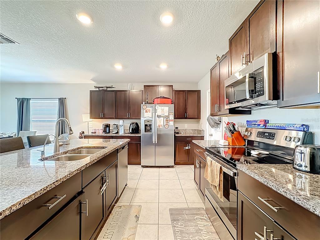1511 Tiger Tooth Place Ruskin, FL 33570 - Photo 19 of 59 a kitchen with stainless steel appliances granite countertop a sink stove and refrigerator