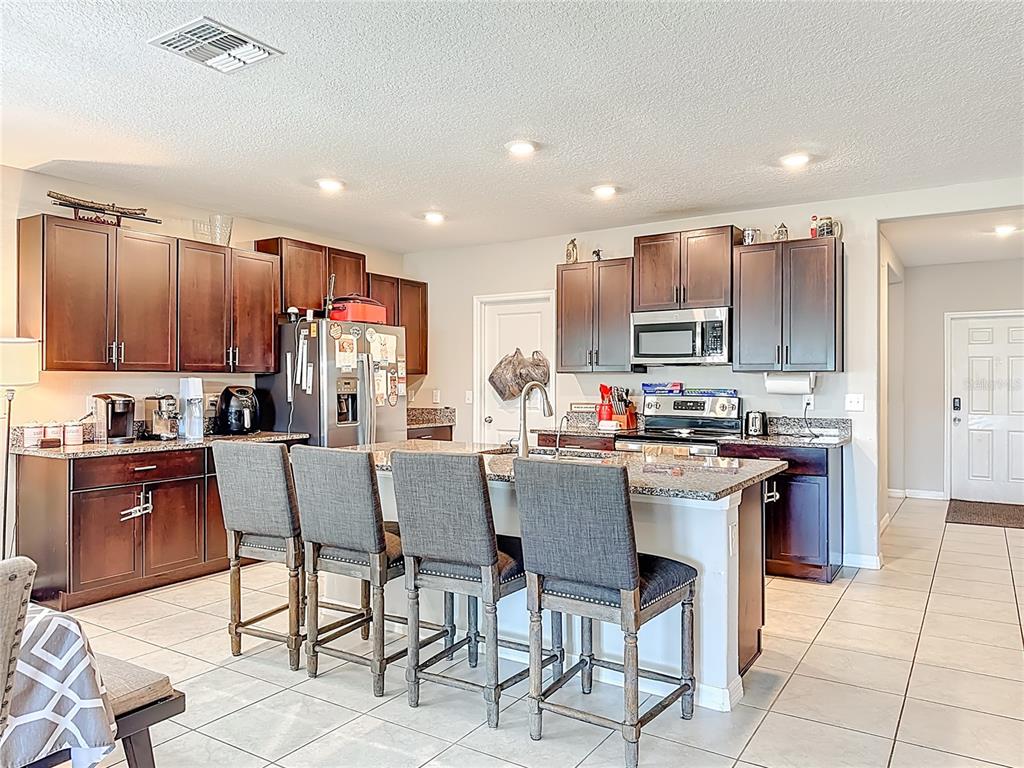 1511 Tiger Tooth Place Ruskin, FL 33570 - Photo 22 of 59 a kitchen with stainless steel appliances kitchen island granite countertop a sink a stove a dining table and chairs