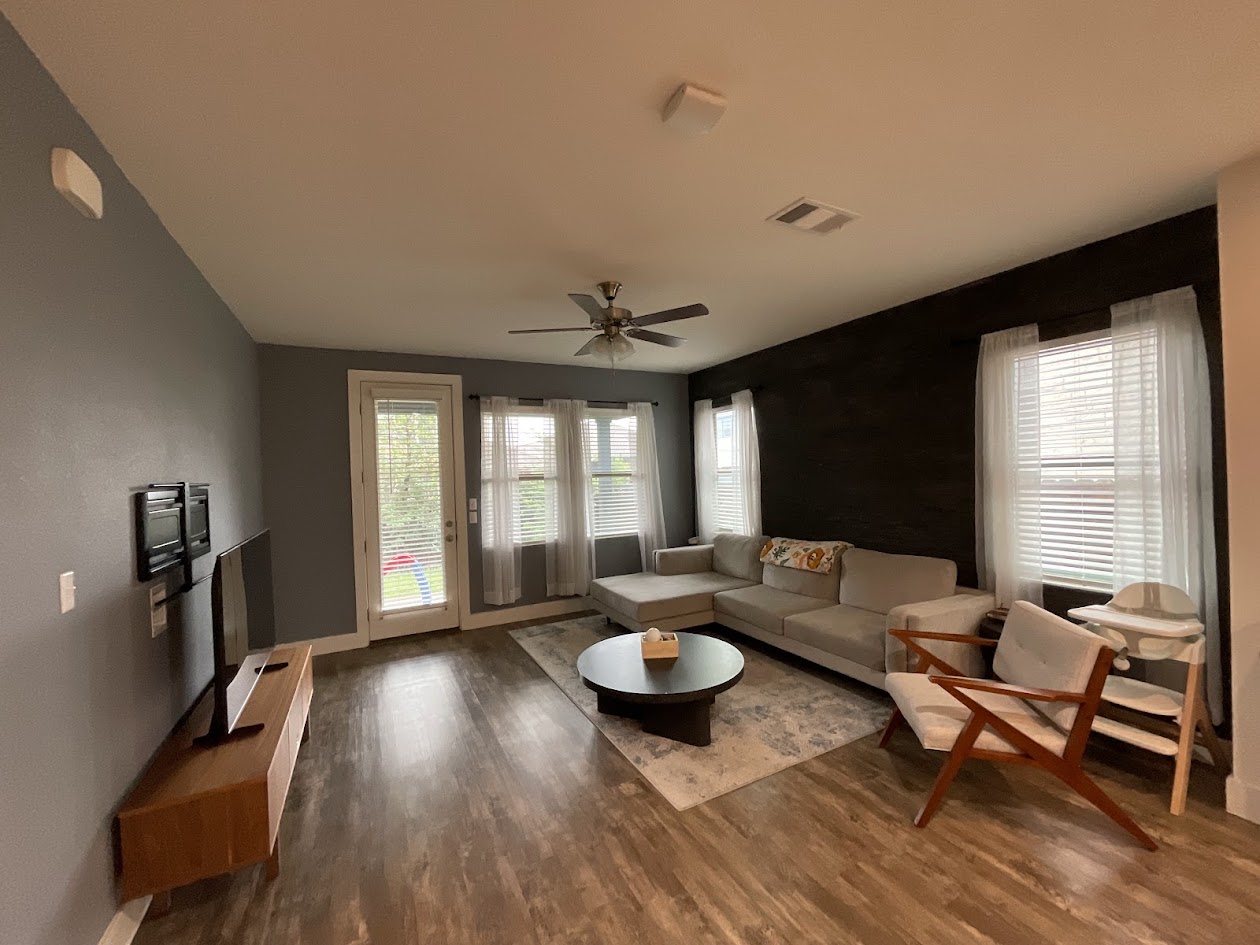 624 Golden Glory Road Leander, TX 78641 - Photo 12 of 39 Spacious living area featuring wood-finish flooring, a ceiling fan, and a prominent dark accent wall