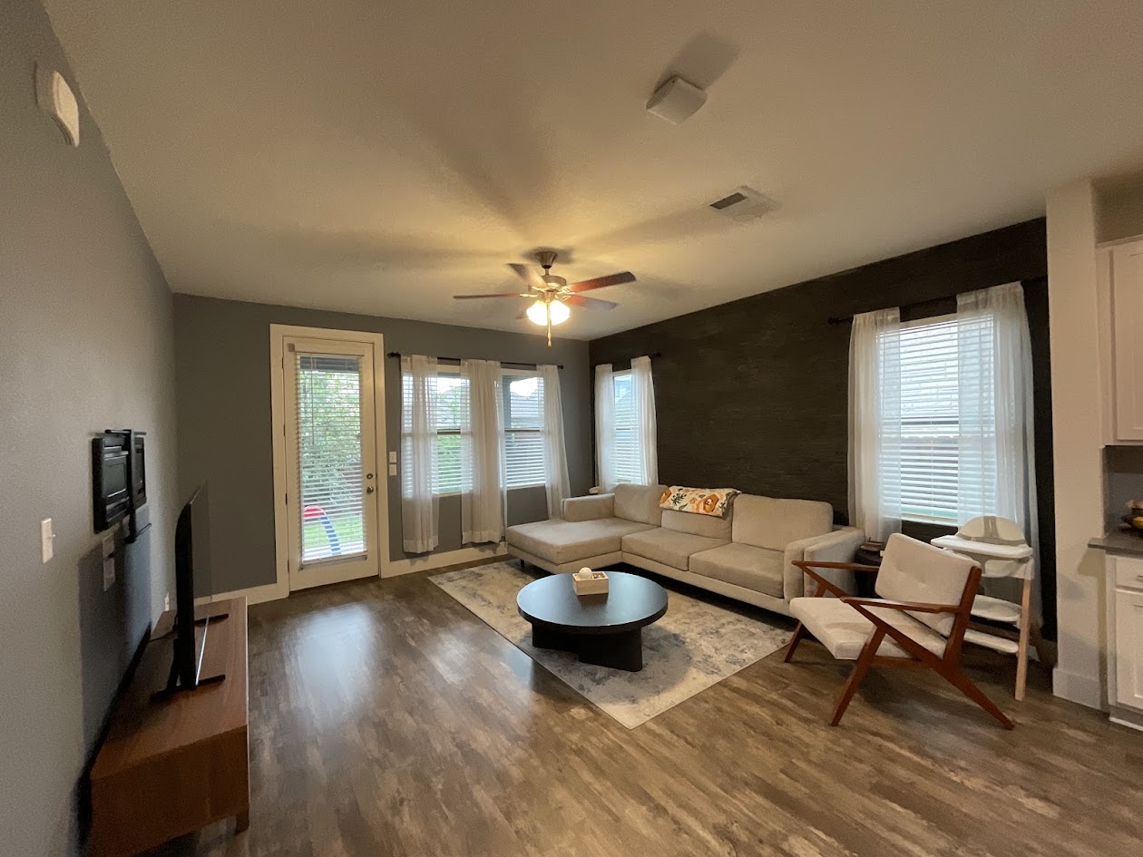 624 Golden Glory Road Leander, TX 78641 - Photo 13 of 39 Spacious living area featuring wood-finish flooring, a ceiling fan with light fixture, and multiple windows providing natural light