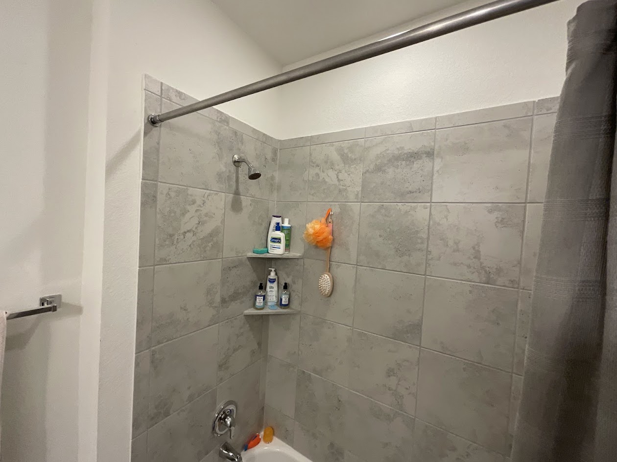 624 Golden Glory Road Leander, TX 78641 - Photo 26 of 39 Tile-surround shower featuring a built-in corner shelf and a chrome shower head with coordinating fixtures