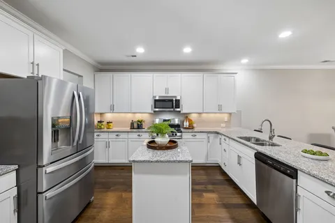 a kitchen with a refrigerator a stove top oven a sink and cabinets