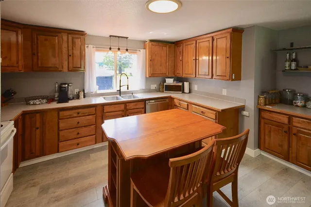 a kitchen with stainless steel appliances granite countertop a table chairs sink refrigerator and cabinets