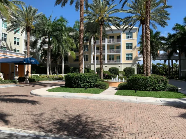 front view of a house with a yard and palm trees