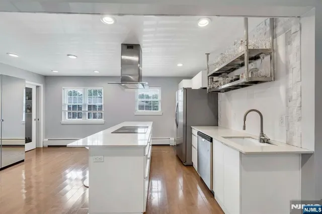 a kitchen with stainless steel appliances a sink dishwasher a stove a refrigerator with wooden cabinets and floor