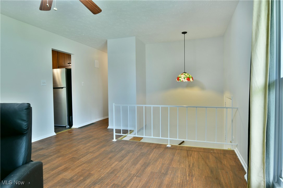 234 Howland Wilson Road Northeast Warren, OH 44484 - Photo 8 of 37 Empty room featuring dark wood-style flooring, a ceiling fan, and a textured ceiling