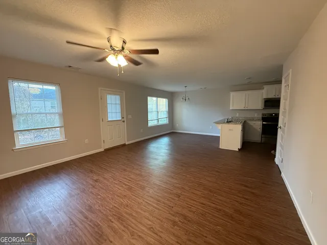 a view of a room with wooden floor and a ceiling fan