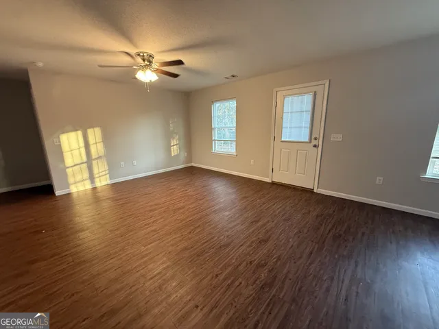 a view of an empty room with wooden floor and a window