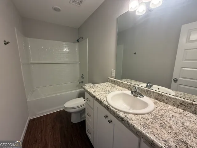 a bathroom with a sink a toilet a mirror and shower
