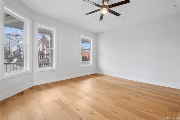 a view of an empty room with a window and wooden floor