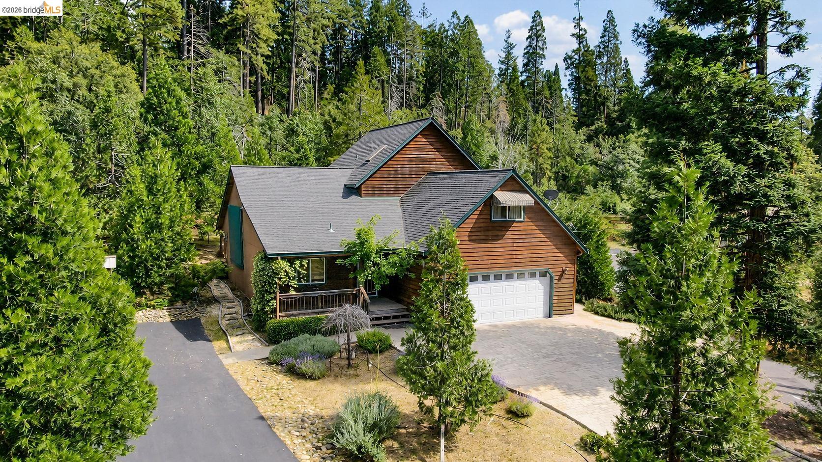 22401 Ridge Road Twain Harte, CA 95383 - Photo 1 of 56 Wood-sided residence featuring a two-car garage, dark asphalt shingle roofing, and natural landscaping