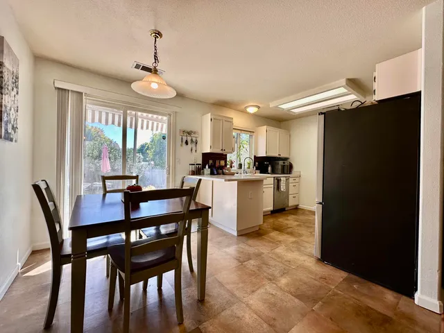a kitchen with a dining table chairs and refrigerator
