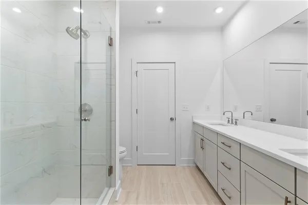 a spacious bathroom with a double vanity sink a mirror and shower