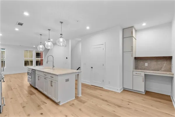 a large kitchen with a large counter top a sink stainless steel appliances and cabinets