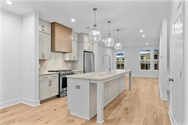 a large white kitchen with stainless steel appliances granite countertop a sink a stove and a refrigerator