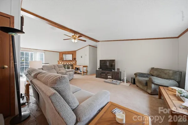 a living room with furniture a flat screen tv and a refrigerator