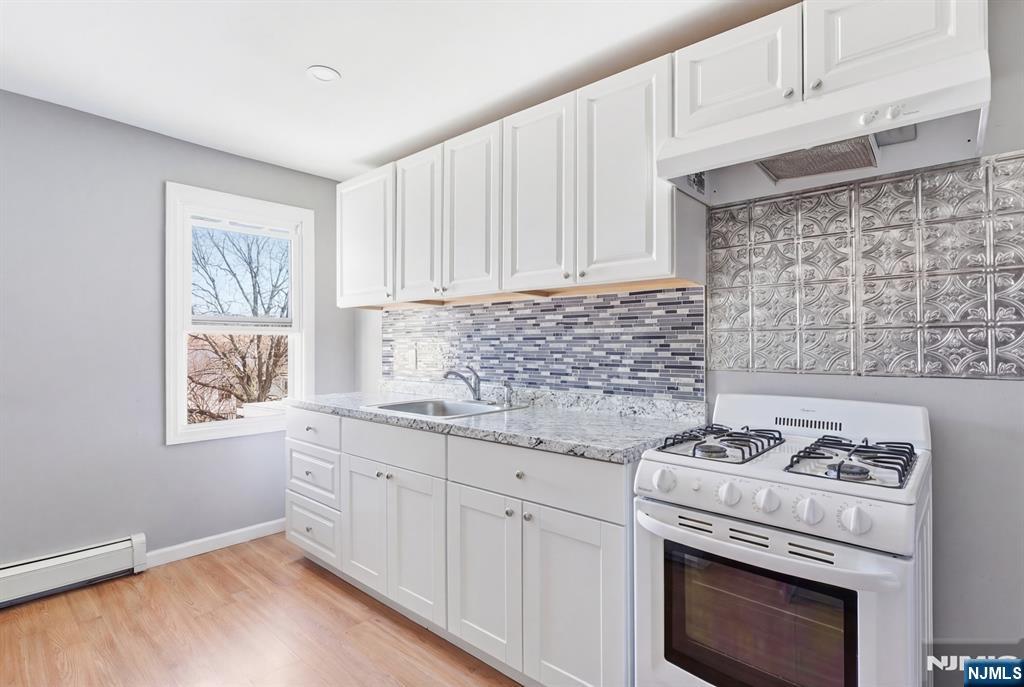 61 Cutler Street Newark, NJ 07104 - Photo 13 of 22 a kitchen with granite countertop a stove sink and cabinets