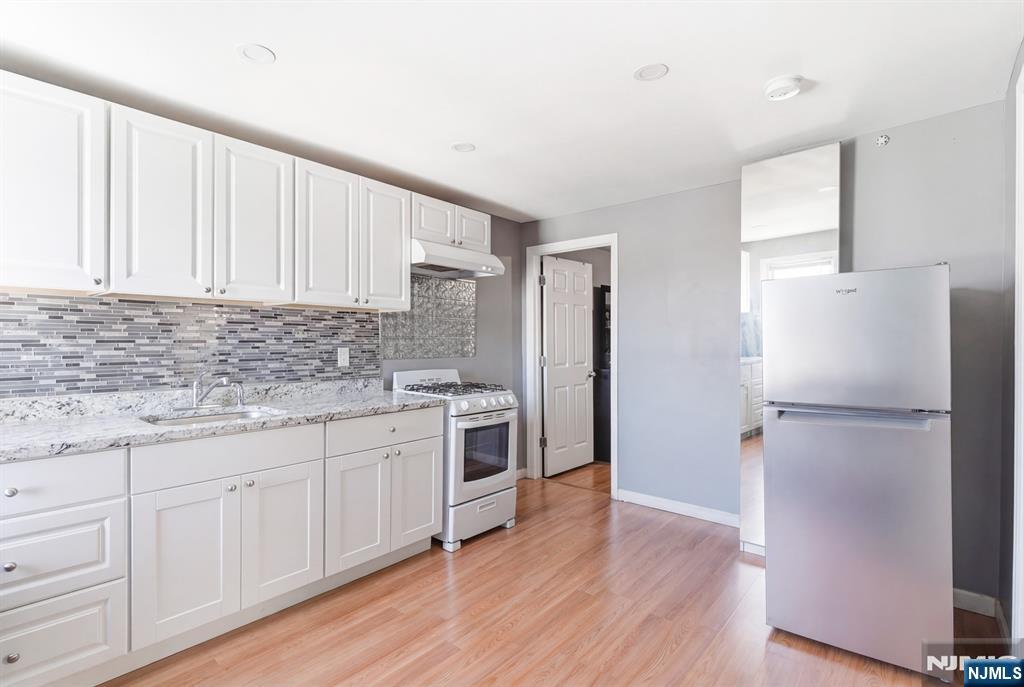 61 Cutler Street Newark, NJ 07104 - Photo 14 of 22 a kitchen with a refrigerator white cabinets and wooden floor