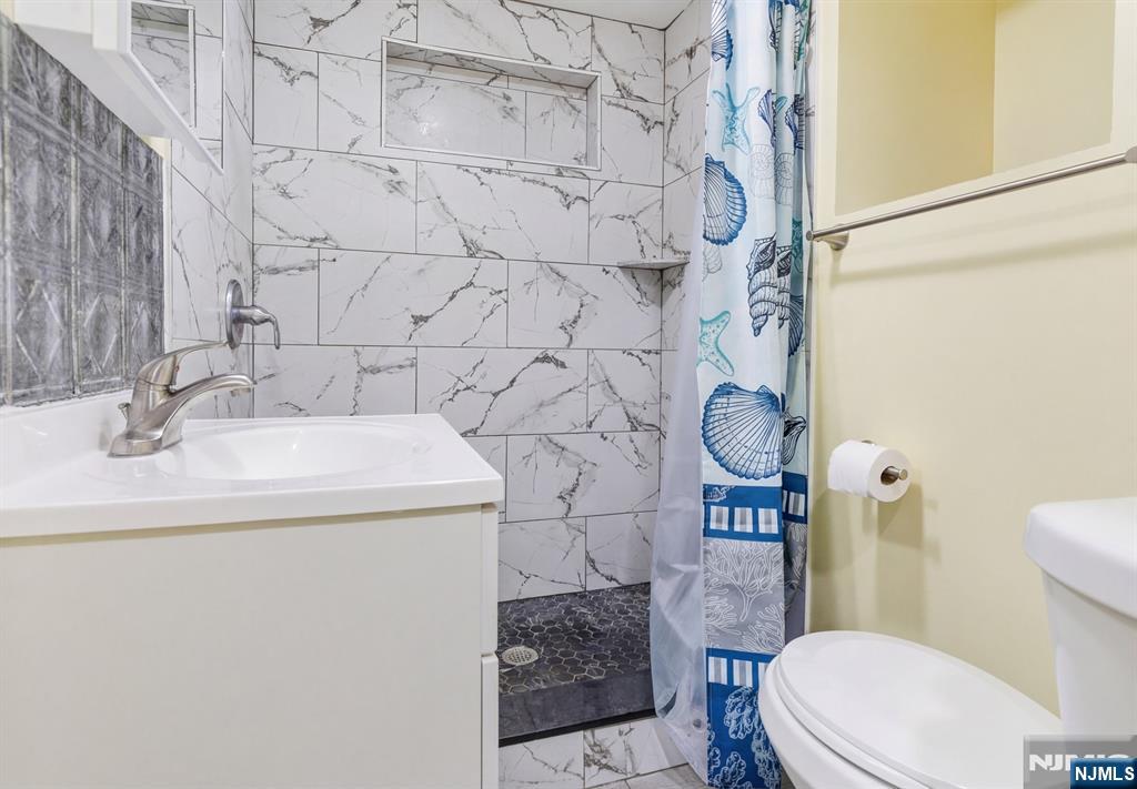 61 Cutler Street Newark, NJ 07104 - Photo 5 of 22 a bathroom with a sink a toilet and shower curtain