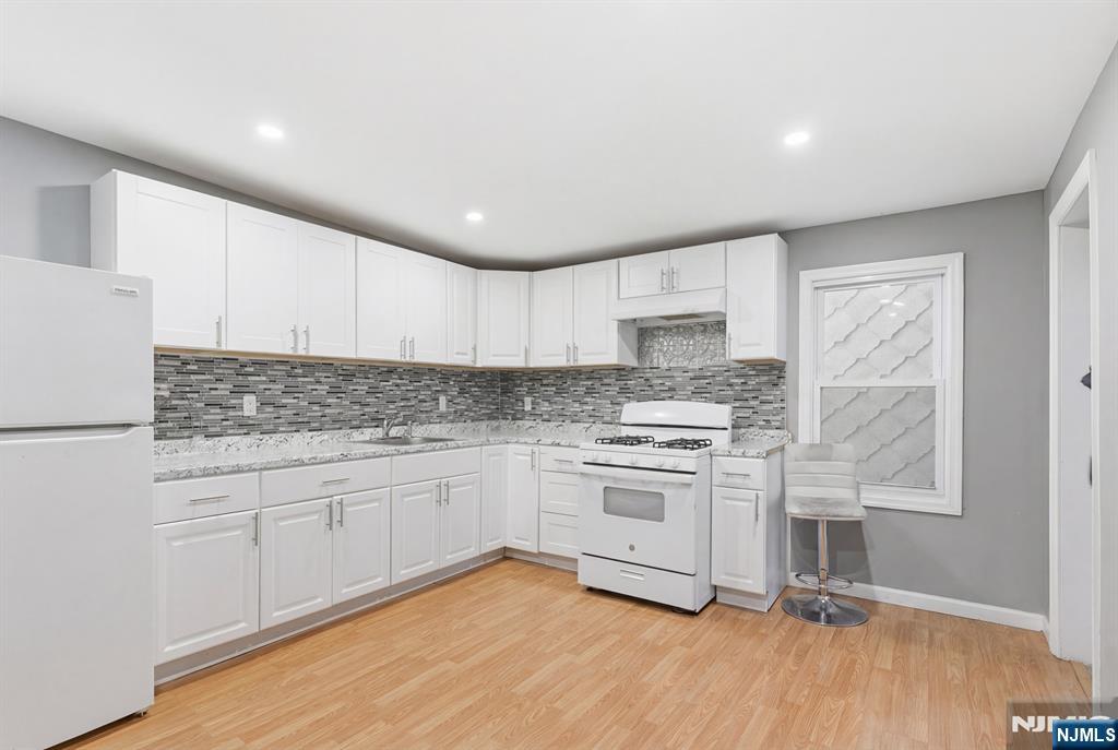 61 Cutler Street Newark, NJ 07104 - Photo 7 of 22 a kitchen with granite countertop white cabinets and white appliances