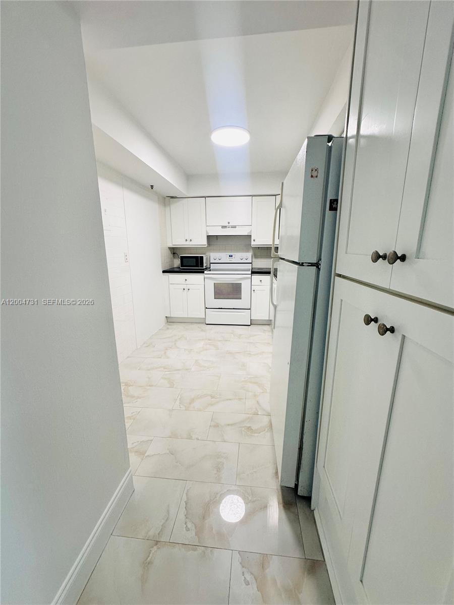 9511 Collins Avenue, Unit 1001 Surfside, FL 33154 - Photo 14 of 34 a kitchen with granite countertop a refrigerator sink and cabinets