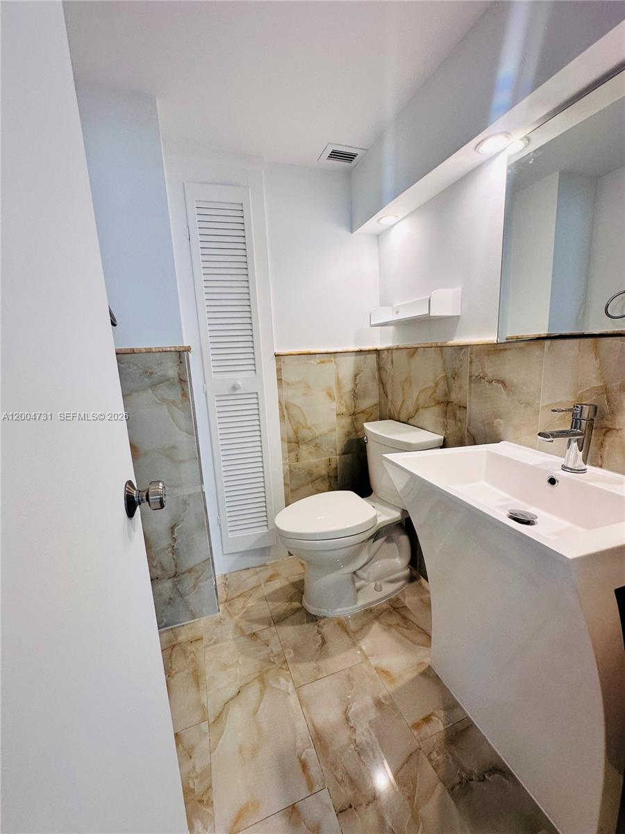9511 Collins Avenue, Unit 1001 Surfside, FL 33154 - Photo 18 of 34 a bathroom with a sink and mirror with toilet