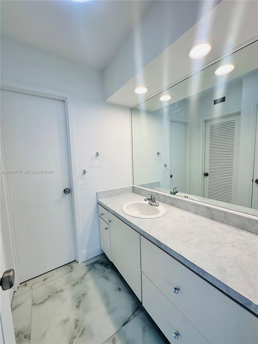 9511 Collins Avenue, Unit 1001 Surfside, FL 33154 - Photo 19 of 34 a bathroom with a granite countertop sink and a mirror