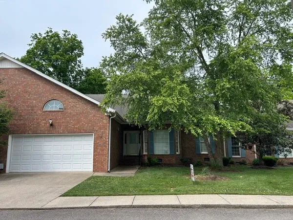a front view of a house with a garden and trees