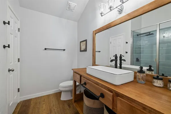 a bathroom with a sink a toilet a mirror and shower